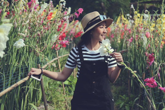outdoor portrait of a beautiful Asian woman wearing hat of smile happy. attractive sexy girl in a field with flowers colorful