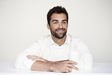 Dude in white sweater holding cup, smiling