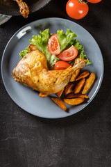 Roasted chicken legs with potato wedges and tomatoes