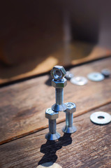 A figure of one small robot assembled from several bolts and nuts standing in a vertical position on a table made of planks. It symbolizes technology, progress, engineering and industrialization