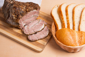 Baked pork with herbs and spice on wooden board and and slices w