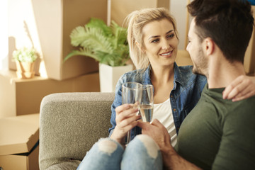 Couple chilling on the sofa with drinks .