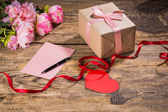 The gift box with hearts on wooden background