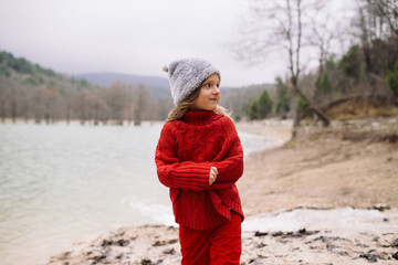 little cute girl in a red clothes on the lake