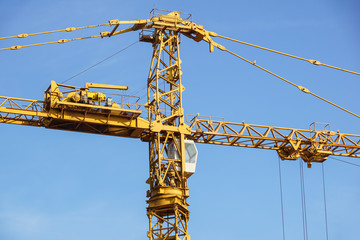 Part of yellow construction tower crane arm against blue sky