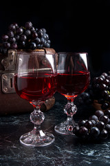 Glass of red wine on dark marble background. Cluster of blue gra