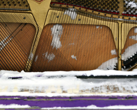Vintage Piano musical instrument under the snow.