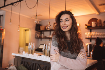 Young woman seller standing in cafe with arms crossed