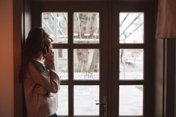 Beautiful young woman in cafe talking by her phone