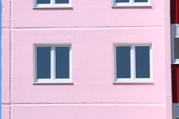 Part of pink residential building with windows with double glazi
