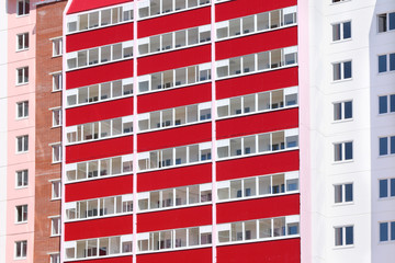 Part of new pink residential building with red balconies  at sun
