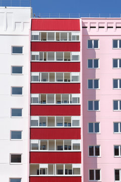 Part of pink residential building with red balconies at sunny da