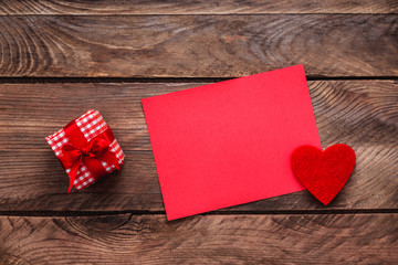 Valentines day greeting card and small gift, heart decoration over wooden background. Top view with copy space