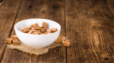 Portion of Caramel pieces on wooden background (selective focus)