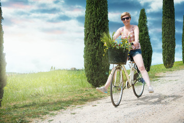 Young beautiful blond woman on vacation in Tuscany, riding a bic