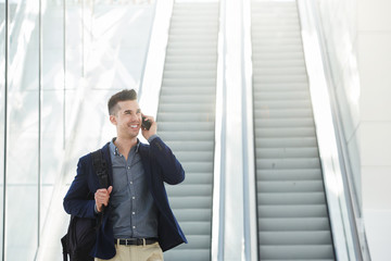 Fototapeta premium Portrait of handsome business man by escalator on phone call