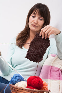 femme mécontente qui a des difficultés pour tricoter un pull