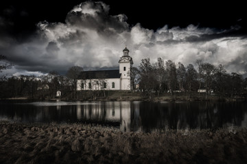 Fototapeta na wymiar White church in black Gothic look with a dramatic dark cloudy sky