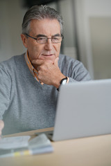 Senior man at home connected on laptop computer