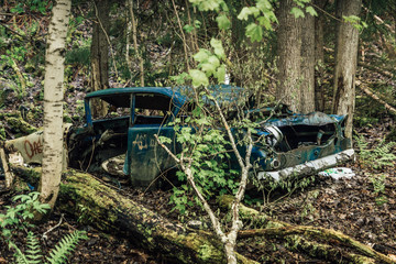 Old abandoned car wreck standing in a forest in Sweden