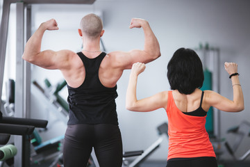 Strong man and a woman posing in the gym