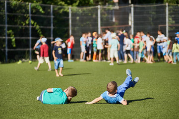 Fototapeta premium Two young little boys lie on grass at football stadium.