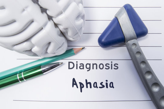 Neurological diagnosis of Aphasia. Neurological reflex hammer, shape of the brain, pen and pencil the lying on a medical report, labeled with diagnosis of Aphasia. Concept for neurology