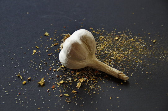strewn spices and garlic on a black background