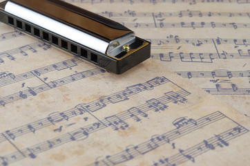 Silver harmonica on vintage classical notes