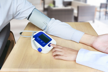 Concept of female doctor press start button on blood pressure