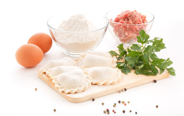 Homemade pelmeni with ingredients on white background