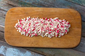 finely chopped crab sticks on cutting board on an old wooden table. close up, top view
