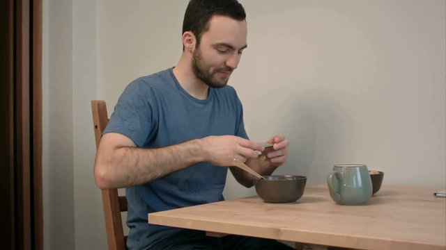 Young man taking photo of breakfast using smartphone