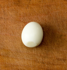 peeled boiled egg on an old cutting board. view from above close-up