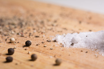 Pepper and salt on a kitchen wooden board.