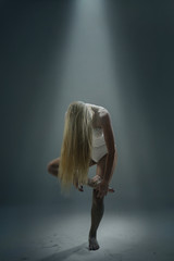 Woman dancer with long blond hair posing in the studio with low