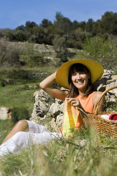 femme souriante assise dans l'herbe qui tricote en été