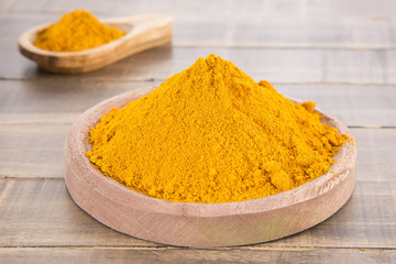 Turmeric powder on the wooden background - Curcuma longa