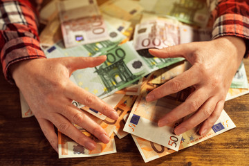 Greedy hands withdrawing pile of euro banknotes cash