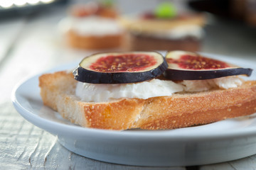 Bruschetta with goat cheese and figs on white plate
