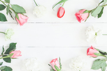 Frame with rose flowers and tulip om wooden white background. Flat lay, top view