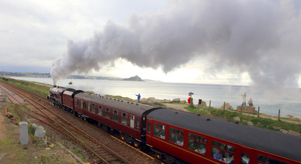 Fototapeta na wymiar Steam train leaving Penzance, with St Michael's Mount, Mounts Bay, Cornwall, England, UK.