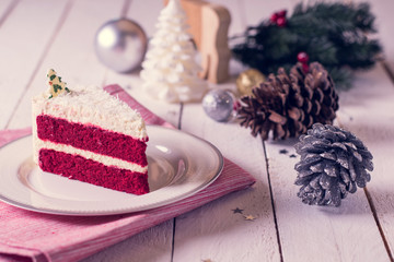Christmas cake on plate on red fabric on wood background and dec