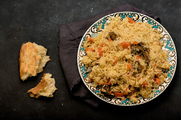 Pilaf on plate with oriental ornament and Traditional Asian breads - churek. Plov. Top view.