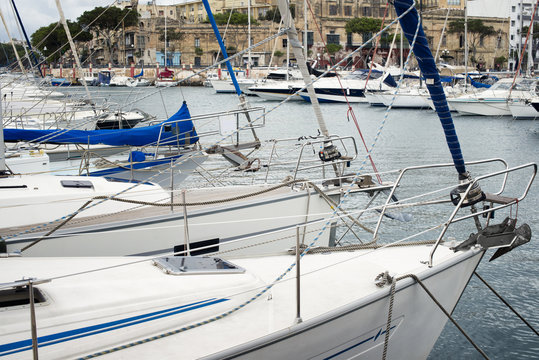 Yachts moored at Msida Marina in Malta. Sail boats in a row on docks at seaside harbor.
