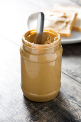 Peanut butter jar and toasts on wooden table. Copyspace.
