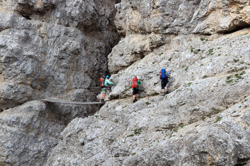People climbing the Via Ferrata Severino Casara with bridge in Sexten Dolomites mountains, South Tyrol, Italy