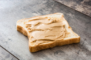Peanut butter and toasts on wooden table.
