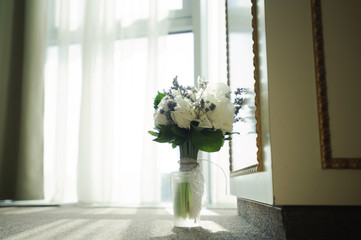 Wedding flowers for bride. Woman holding colorful bouquet standin near window, on  day.
