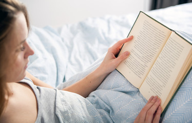 Girl reading book in bed at home